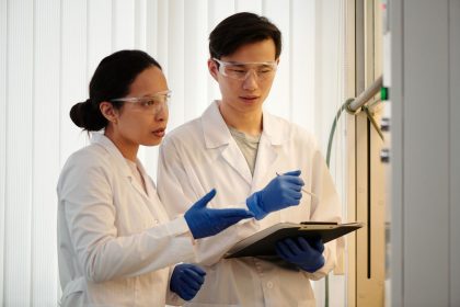 Pesquisadores usando luvas e equipamentos de proteção analisam dados em um laboratório.