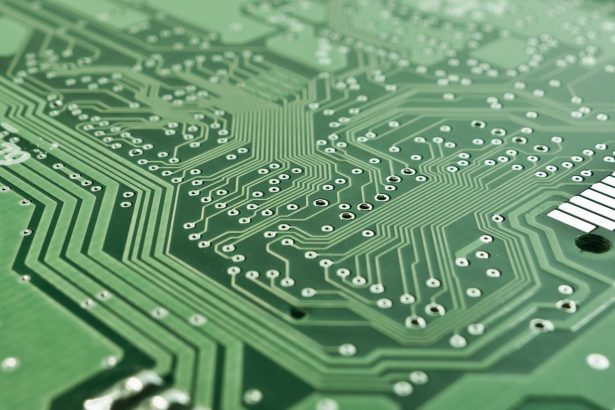 Close de uma placa de circuito impresso com chip, trilhas e componentes eletrônicos.
